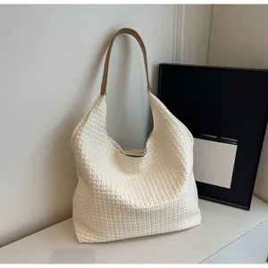 Detail view of white woven leather tote bag with contrasting brown shoulder strap