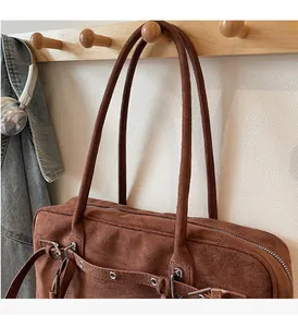 Brown faux suede bowling bag with metal eyelet straps hanging on a wooden hook