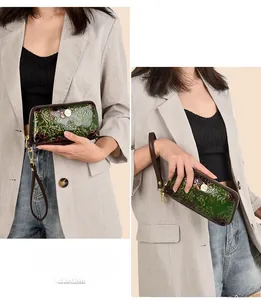 Detail of dark green embossed floral leather clutch with golden zipper and wrist strap