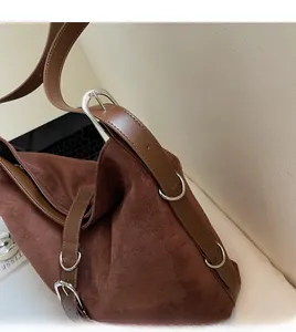 Detail of dark brown faux suede bag featuring smooth leather strap and silver metal hardware