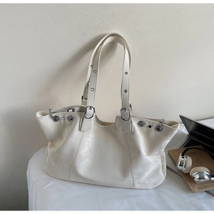 Makroaufnahme der weißen Ledertasche mit silbernen Metallösen und verstellbarem Schnallenriemen