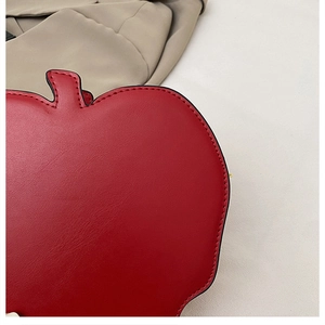 Detail shot of meticulous red stitching on the apple-shaped faux leather shoulder bag