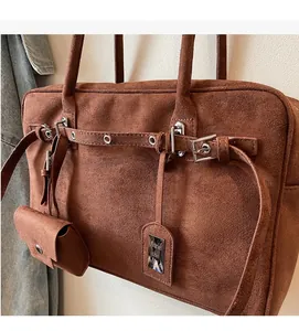 Detailed macro of brown suede tote bag featuring decorative straps and metal buckles