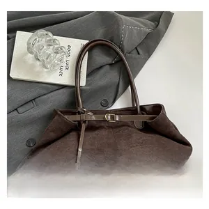 Dettaglio della borsa tote in pelle scamosciata marrone scuro su un blazer grigio