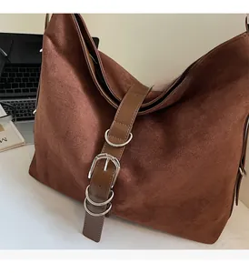Detail view of dark brown suede hobo bag with silver buckles and leather strap accents