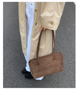 Streetstyle-Aufnahme einer dunkelbraunen Wildleder-Unterachseltasche mit schmalen Riemen