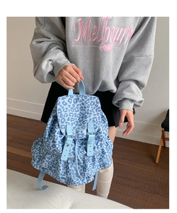 Close-up of light blue leopard print backpack with ruffle hem and leather buckles