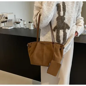 Close-up of brown suede tote bag with matching zipper pouch against a vintage cafe background