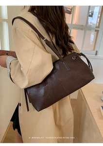 Brown vintage leather shoulder bag styled with a beige trench coat for a casual look