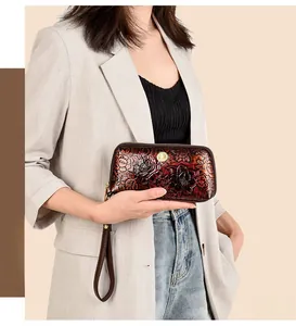 Detail of red-brown embossed floral leather wristlet with secure zipper closure