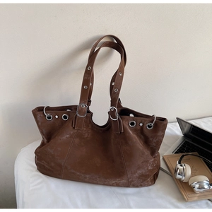 Detailansicht der braunen Vintage-Einkaufstasche mit silbernen Ösen und Schnallenriemen