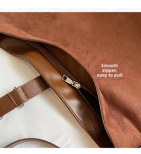 Close-up of smooth metal zipper and brown suede texture on a large bucket bag
