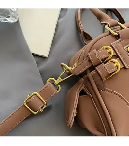 Close-up of brown matte leather bowling bag with gold hardware and adjustable strap