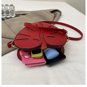 Detail showing red leaf crossbody bag with glitter veins and interior storage capacity