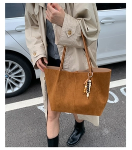 Detail of brown faux suede tote bag with colorful wooden bead charm in a street style setting
