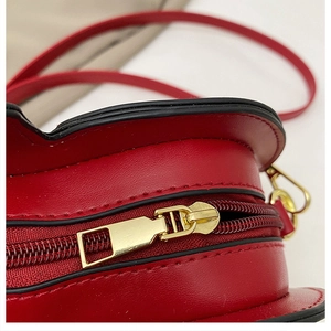Close-up of golden zipper on red heart-shaped PU leather bag with detailed stitching