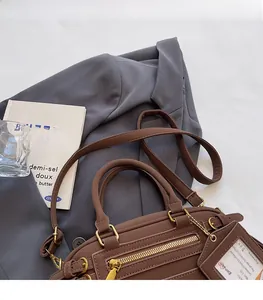 Detail of brown faux leather bowling bag with adjustable strap and small card holder tag