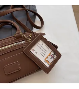 Detail of a brown PU leather bag with metal zipper and a cute bear card sleeve pendant