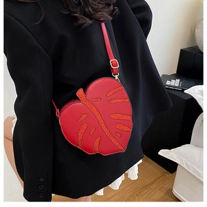 Detail of red leaf-shaped crossbody bag with glitter accents and adjustable strap