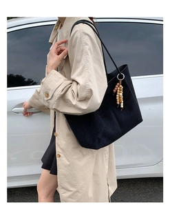 Detail of matte black oversized tote bag with wooden bead charm in a lifestyle shot