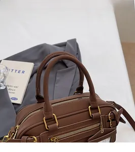 Detail of caramel leather boston bag with golden hardware and smooth top handles