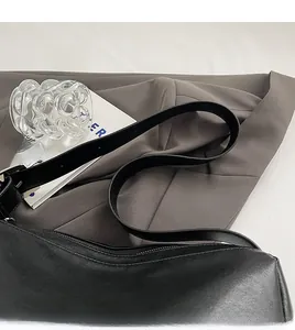 Detail of wide shoulder strap on black leather tote bag with smooth matte texture