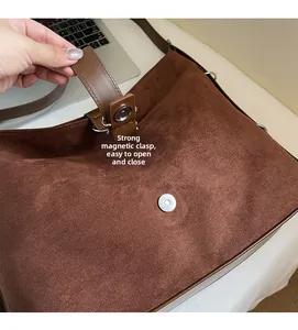 Detail of strong magnetic buckle closure on large brown suede crossbody bucket bag
