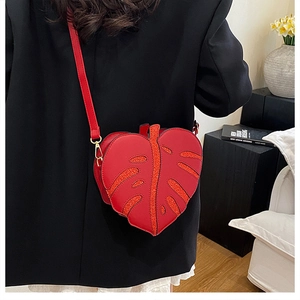 Detail of red leaf-shaped crossbody bag with glitter textures and gold metal hardware