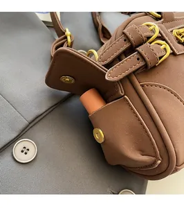 Detail view of the side pocket with golden magnetic buckle on the brown leather handbag