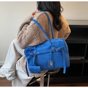 Detail of royal blue suede tote bag with decorative buckle and mini hanging coin purse
