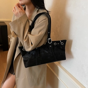 Chic black rivet shoulder bag with silver hardware worn with a beige trench coat