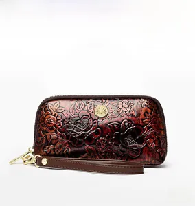 Close-up of retro floral embossed leather wristlet with golden metal emblem and strap