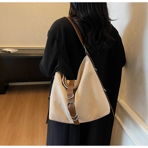 Detailed view of beige suede bucket bag with leather strap and metal ring buckles