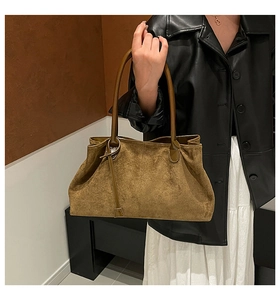 Detalle del bolso tote de ante marrón vintage con hebilla metálica y asa elegante