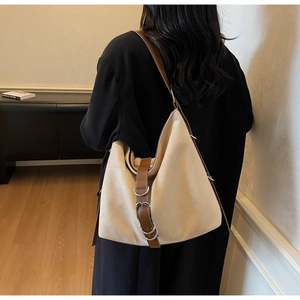 Detail of the large canvas tote bag featuring premium leather trim and metal buckle accents