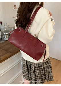Sophisticated burgundy shoulder bag with pleated leather texture worn over a white sweater