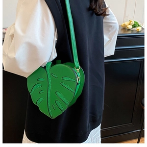 Detail of leaf-shaped crossbody bag featuring glittery texture and gold metal hardware