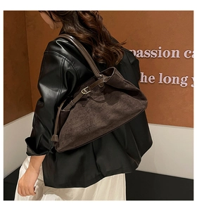 Detalle de un bolso tote grande de ante marrón con correas de cuero y hebillas elegantes