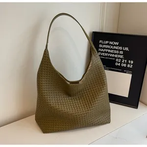 Close-up of deep green woven hobo bag with intricate leather texture on marble surface