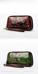 Macro view of embossed floral pattern on leather wristlet wallets with gold metal logos