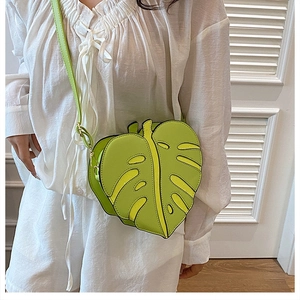 Detail view of a bright green monstera leaf shaped PU leather crossbody bag with leaf vein cutouts