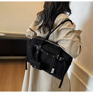 Detail of black suede shoulder bag with decorative buckles and hanging mini coin pouch