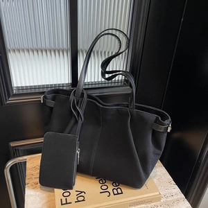 Minimalist black suede tote bag with matching pouch on vintage books and dark wood background