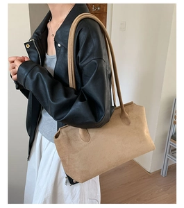 Detail of camel suede tote bag worn on shoulder showing texture and large capacity