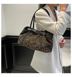 Dettaglio della borsa tote leopardata con manico in pelle nera e fibbia in metallo oro