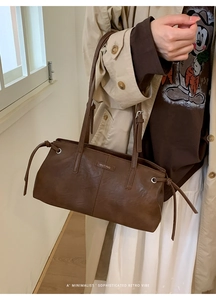 Close-up of minimalist retro brown tote bag with metal brand logo and sleek strap details