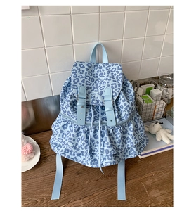 Close-up of light blue leopard print backpack with layered ruffle trim and buckle detail