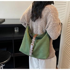 Detail of dark green suede tote bag with brown leather strap and metal buckle closure