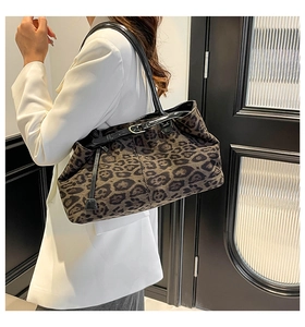 Bolso tote de leopardo con correas de cuero negro al hombro con una chaqueta blanca