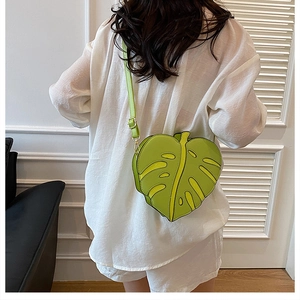 Detail view of a green monstera leaf shaped crossbody bag worn by a model from the back